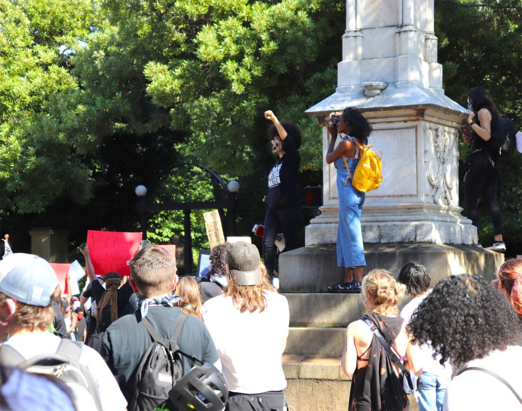 Protesters stand on the Confederate monument