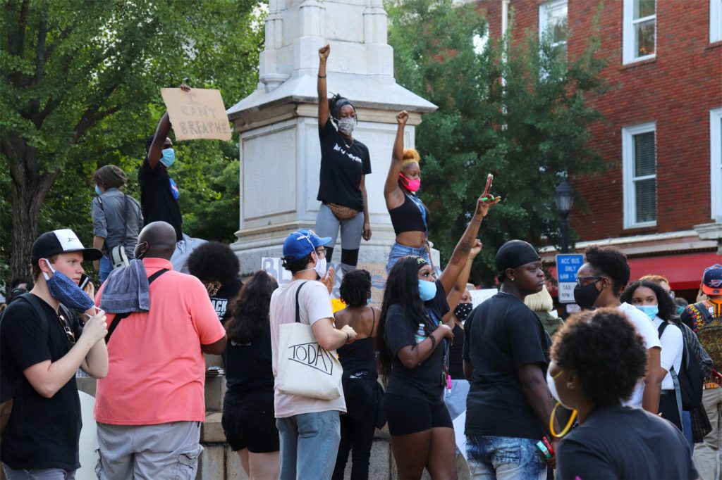Protesters stand on the Confederate monument
