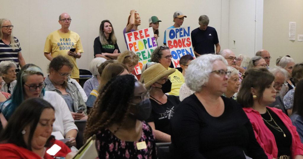 A group of people waiting to speak, some holding signs