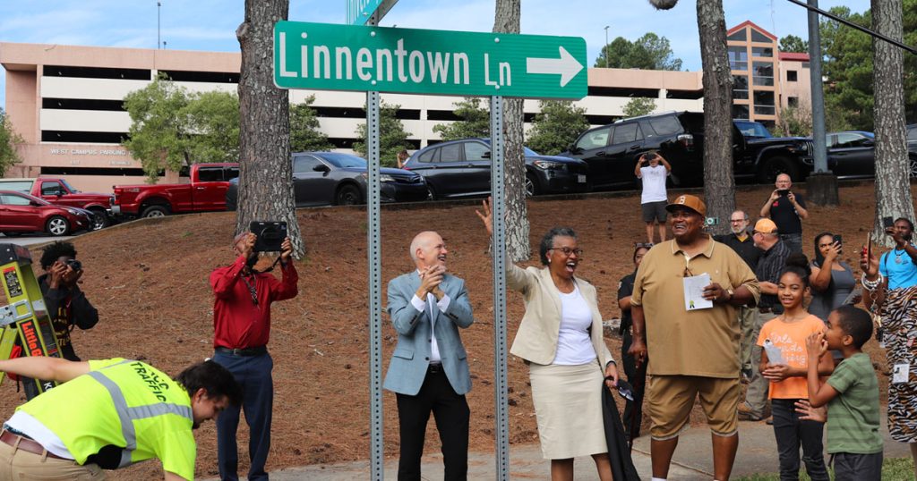 Hattie Thomas Whitehead and Mayor Kelly Girtz cheer underneath a street sign that reads "Linnentown Lane."