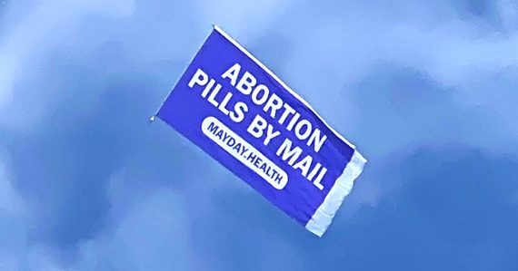 'Abortion pills by mail' banner flying in the clouds